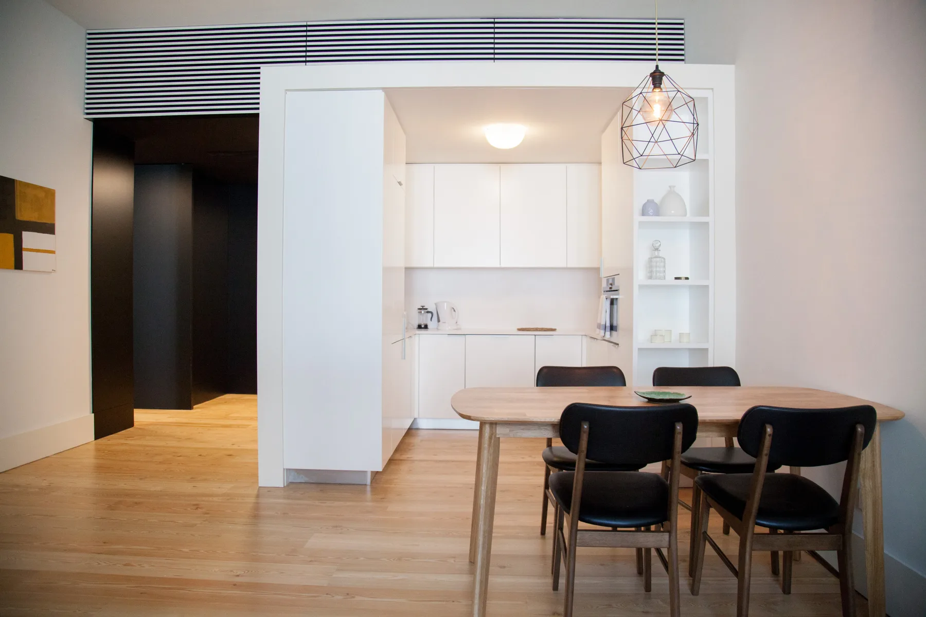 Comedor de concepto abierto con una mesa y una cocina blanca compacta.