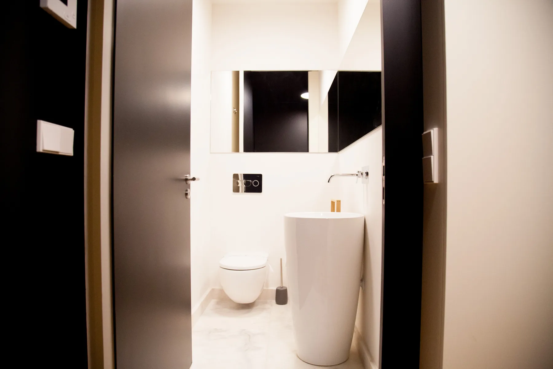 Un baño moderno con un inodoro y un lavabo independiente.