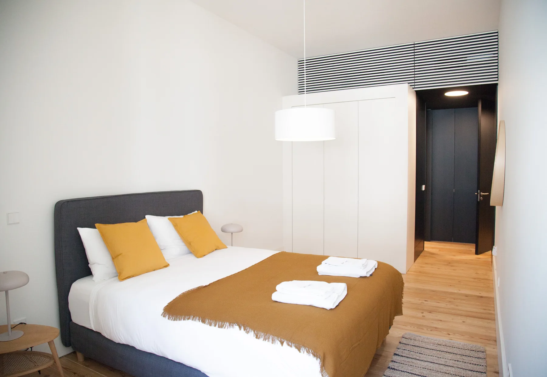 Un dormitorio con una cama bien arreglada y ropa de cama color mostaza.