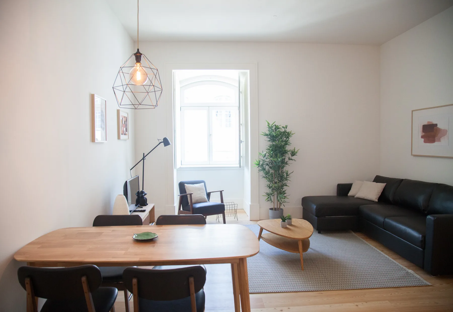 Una luminosa sala de estar y comedor con una mesa de madera y asientos oscuros.