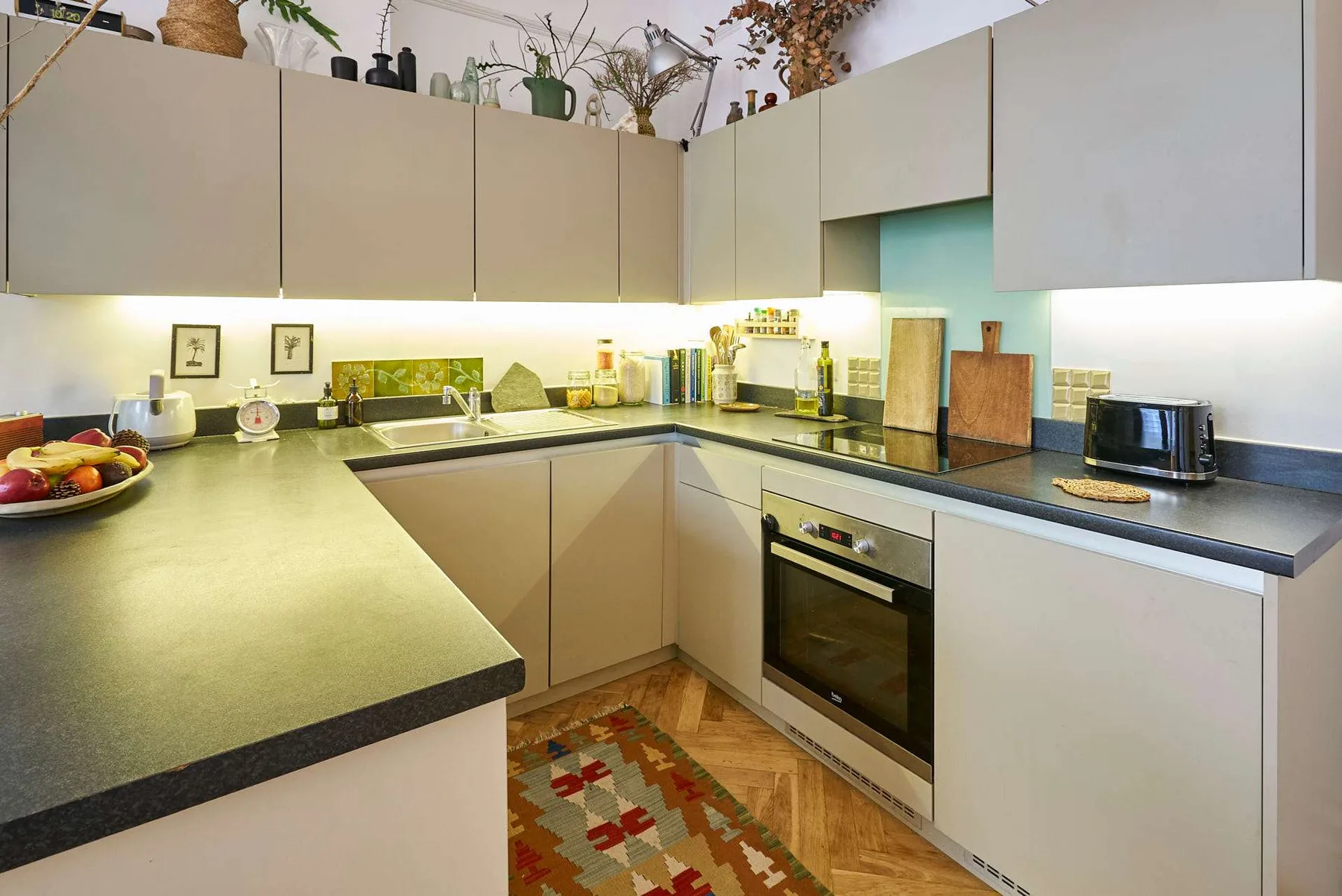 A modern kitchen with pale cabinets, dark countertops, and a built-in oven.