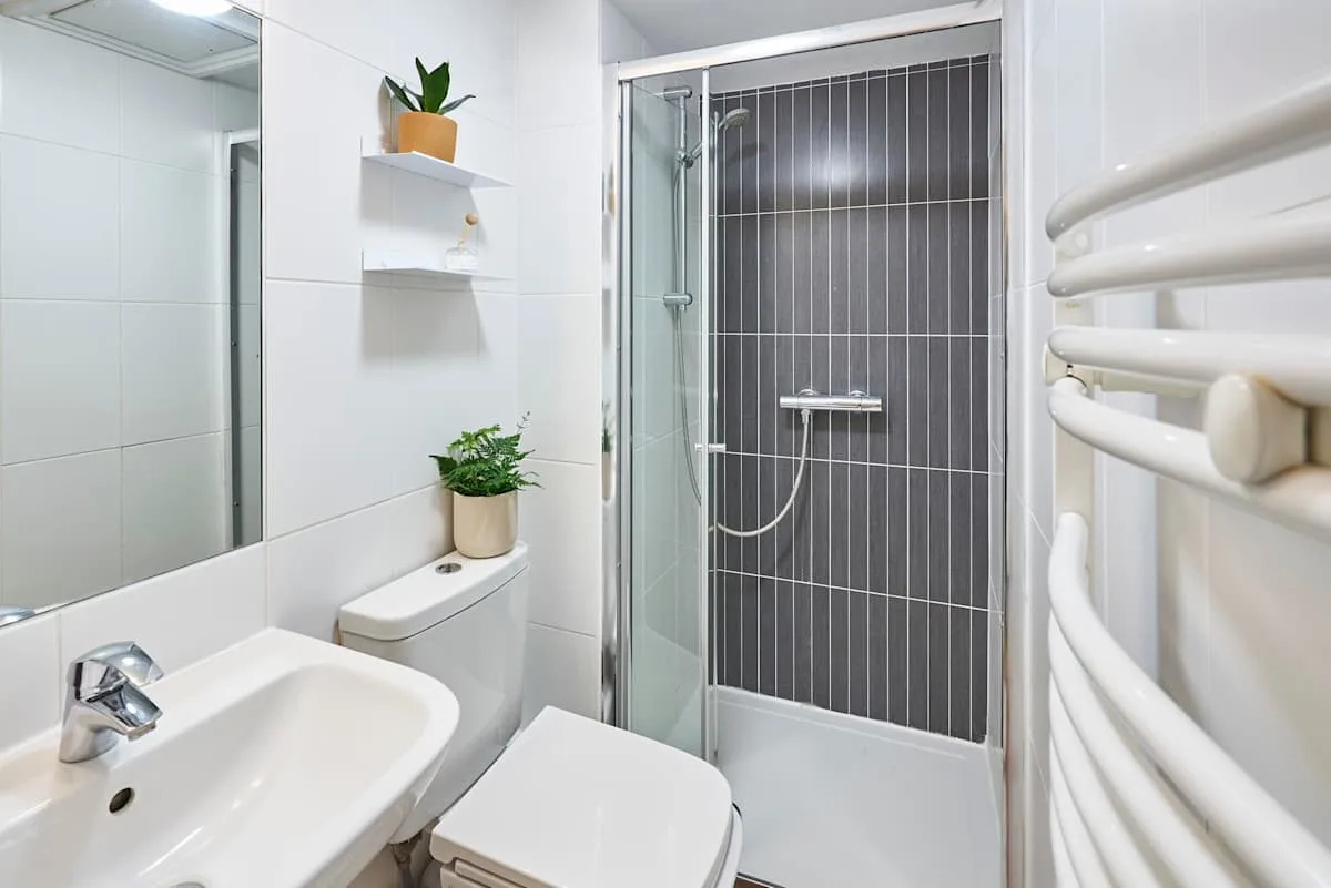 A bright bathroom with a sink, toilet, and glass shower.
