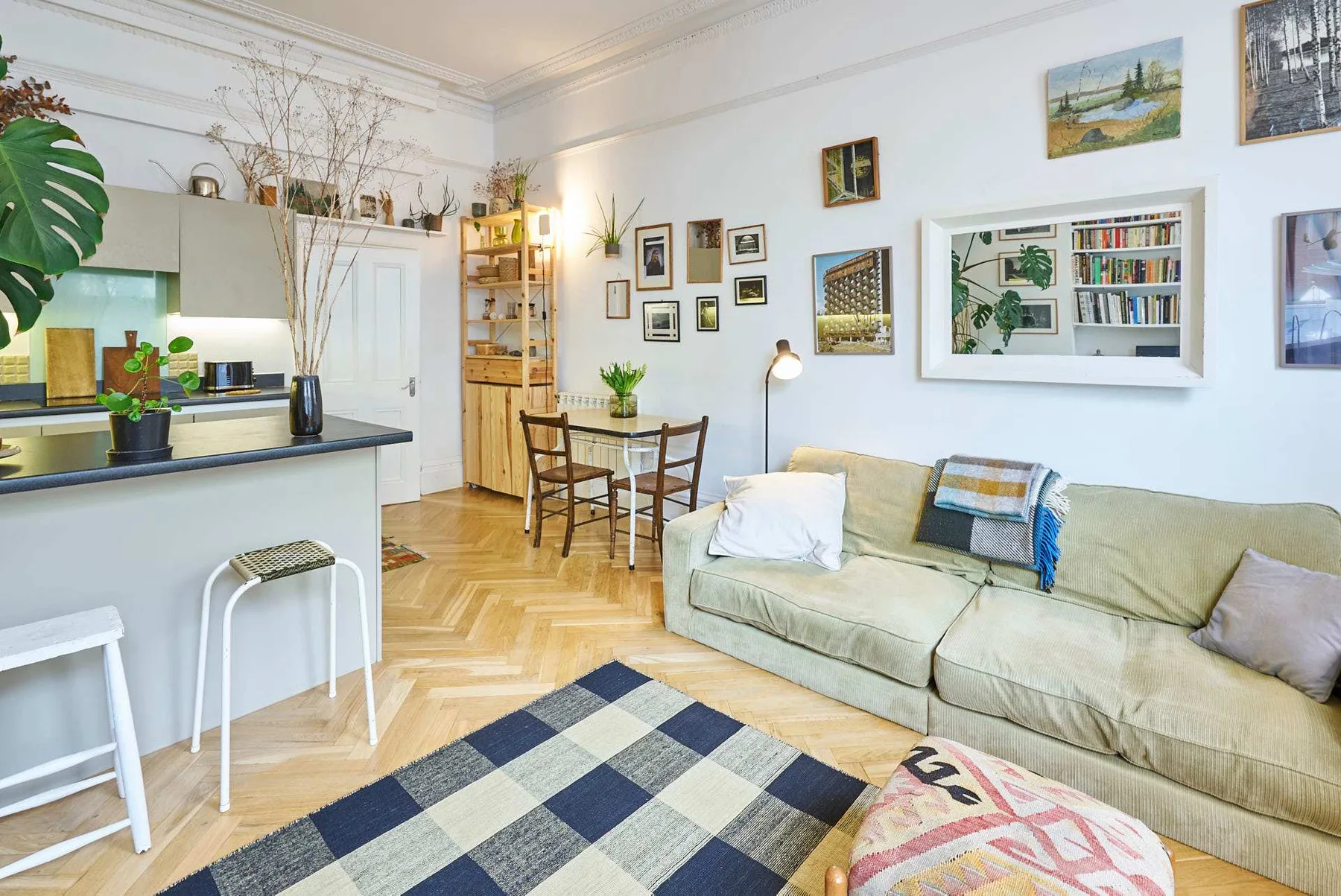A bright living room with a beige sofa and an open kitchen area.