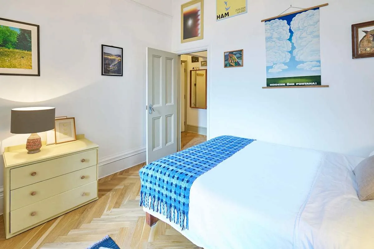 A bedroom with a bed, a dresser, and framed pictures on the walls.