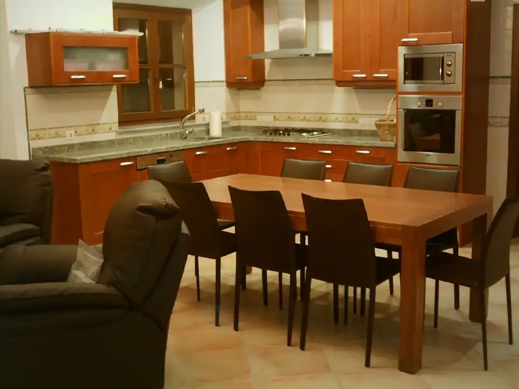 A dining area with a wooden table and dark seating beside a kitchen.