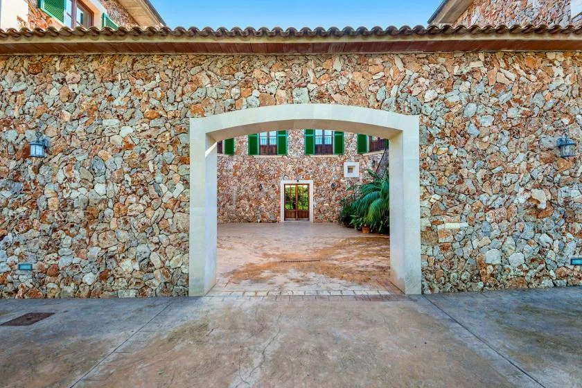 A stone courtyard entrance with a wide open archway and a paved walkway.