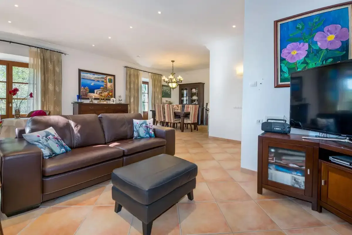 A living room with seating, a television, and a dining area.