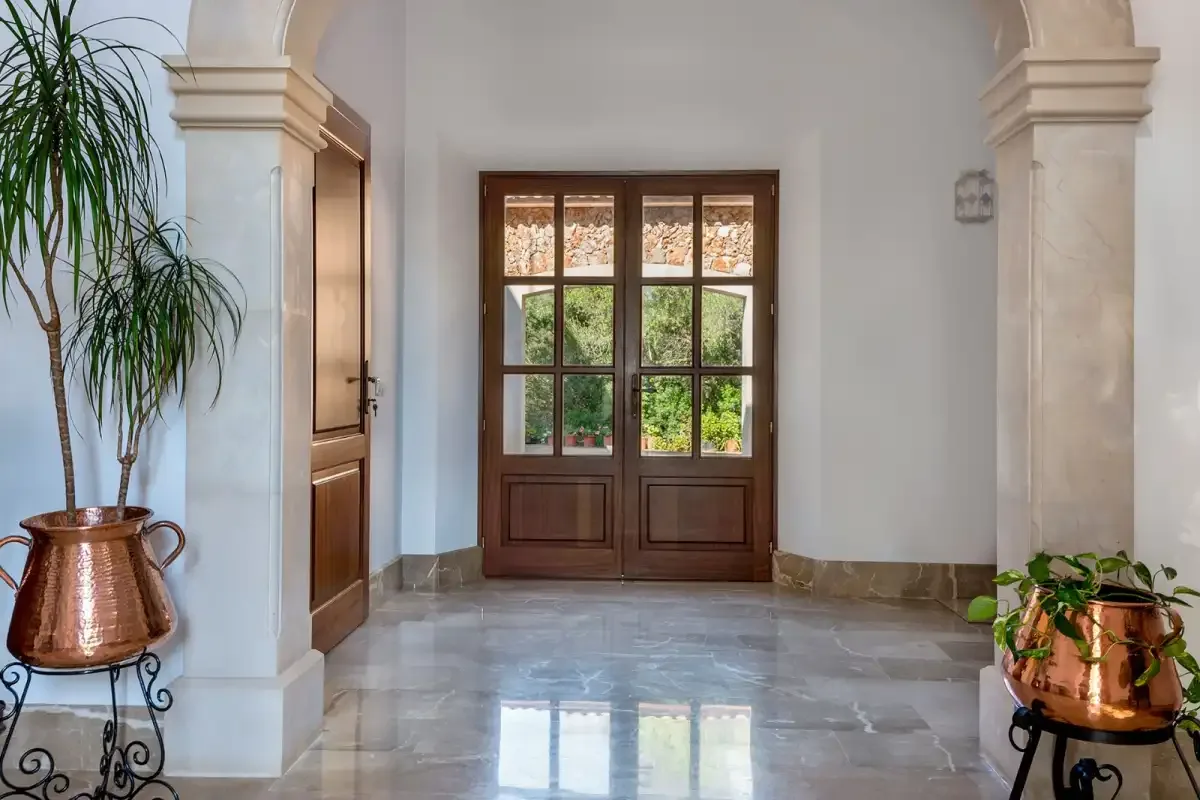 An interior entryway with a wooden double door and potted plants.