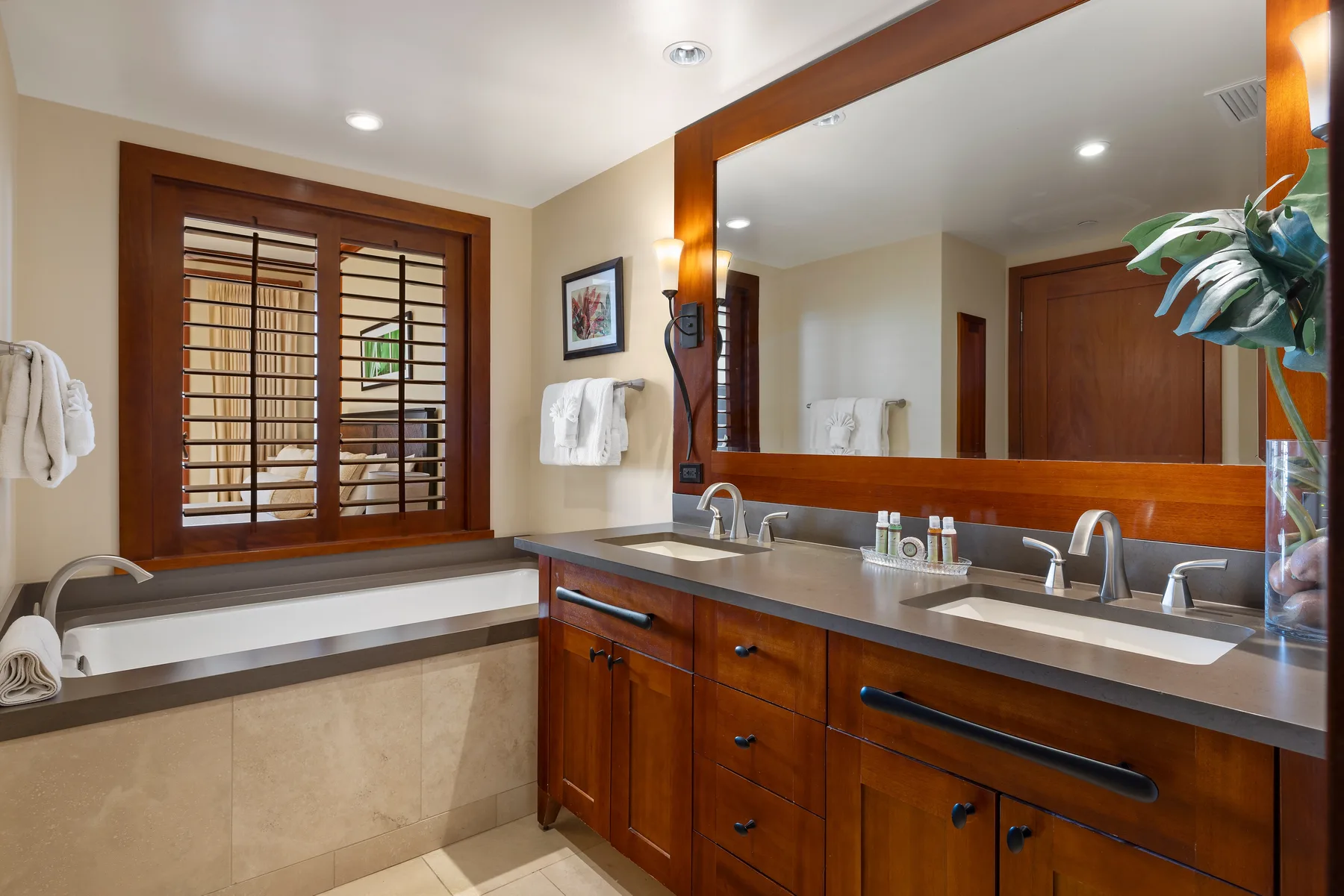 Un baño con bañera, tocador de madera y un espejo grande.