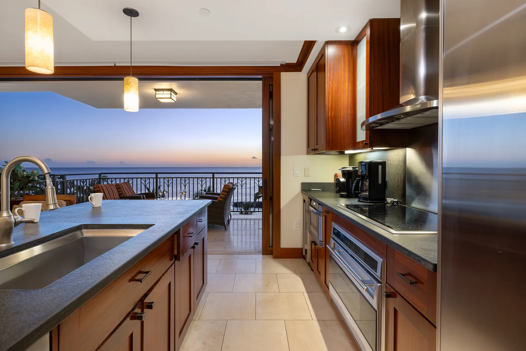 Una cocina con isla central se abre a un balcón con vistas al agua.
