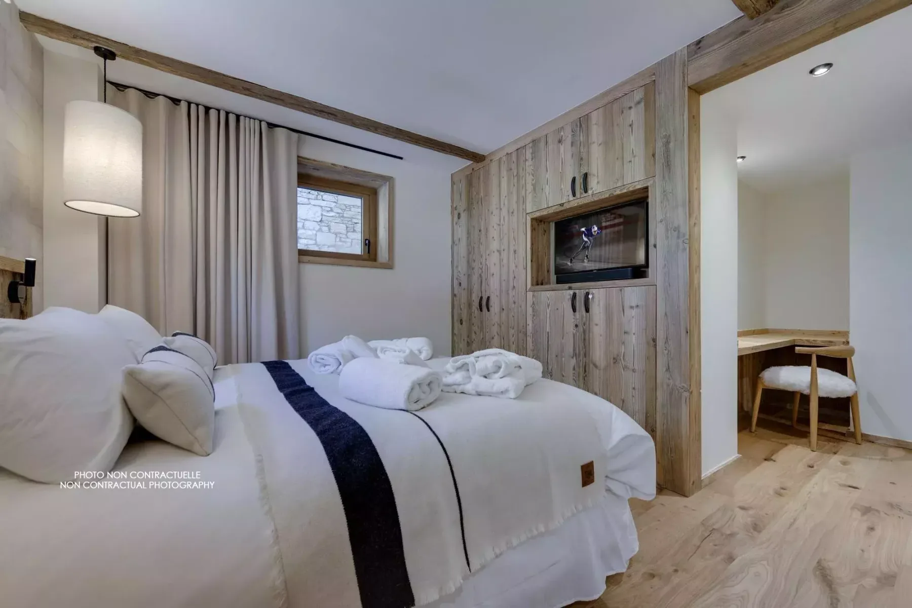 Bedroom with neatly made beds, curtains, and built-in wooden cabinetry.