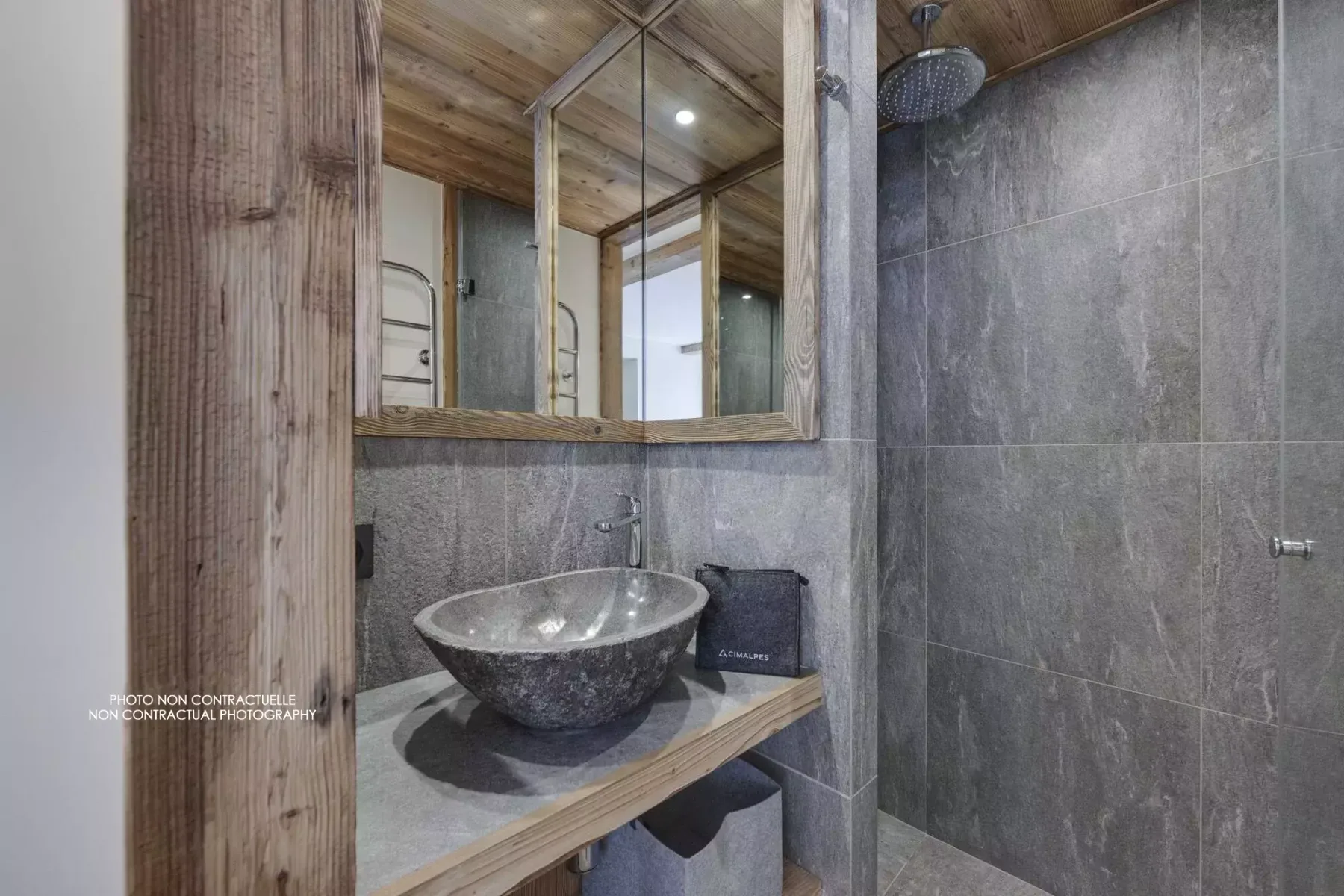 A bathroom with a vessel sink, mirrored cabinet, and tiled shower.