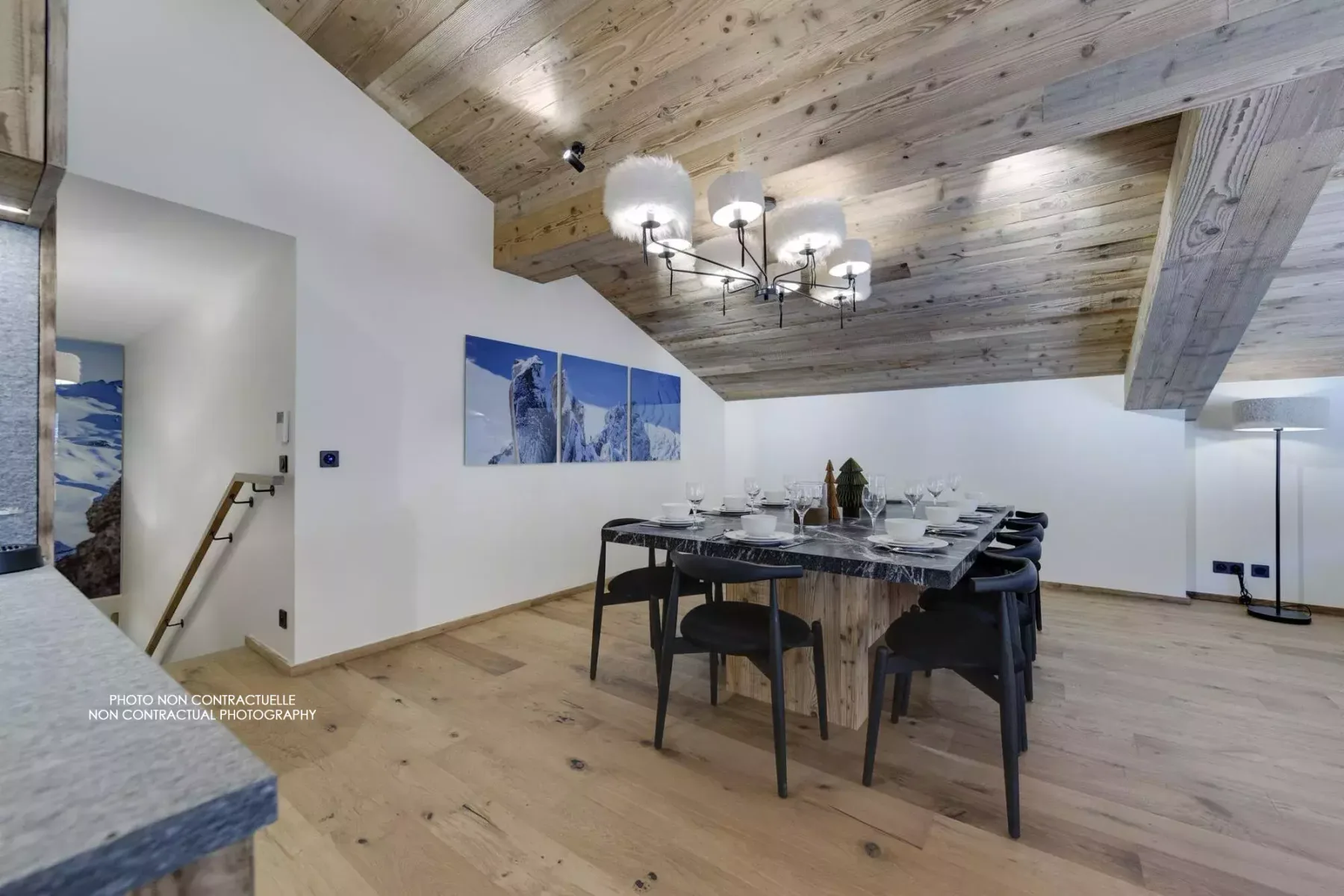 A dining room with a long table and chairs beneath a wood-paneled ceiling.