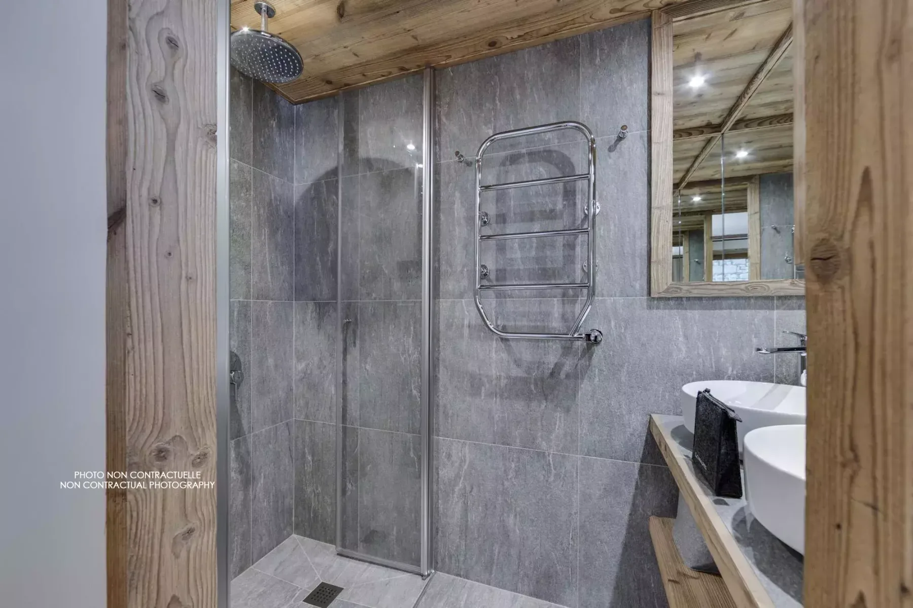 A tiled bathroom with a glass shower and a sink beside a wooden counter.