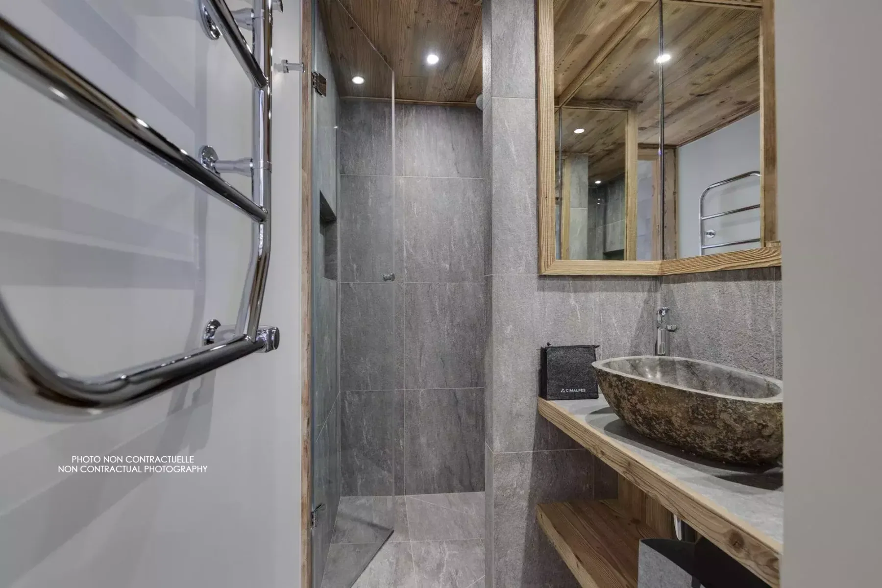 A bathroom with a glass shower, stone sink, and wood-framed mirror.