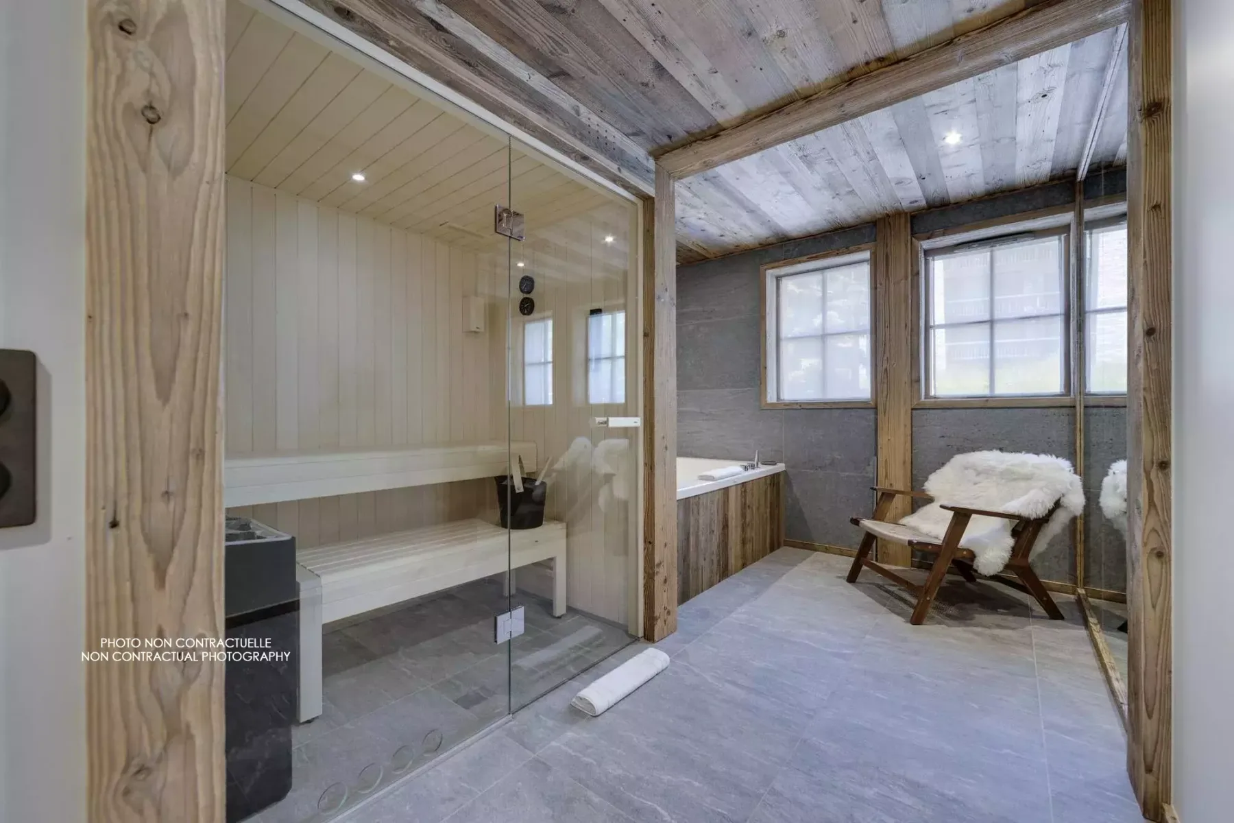 A bathroom with a glass shower beside a seating area and large windows.