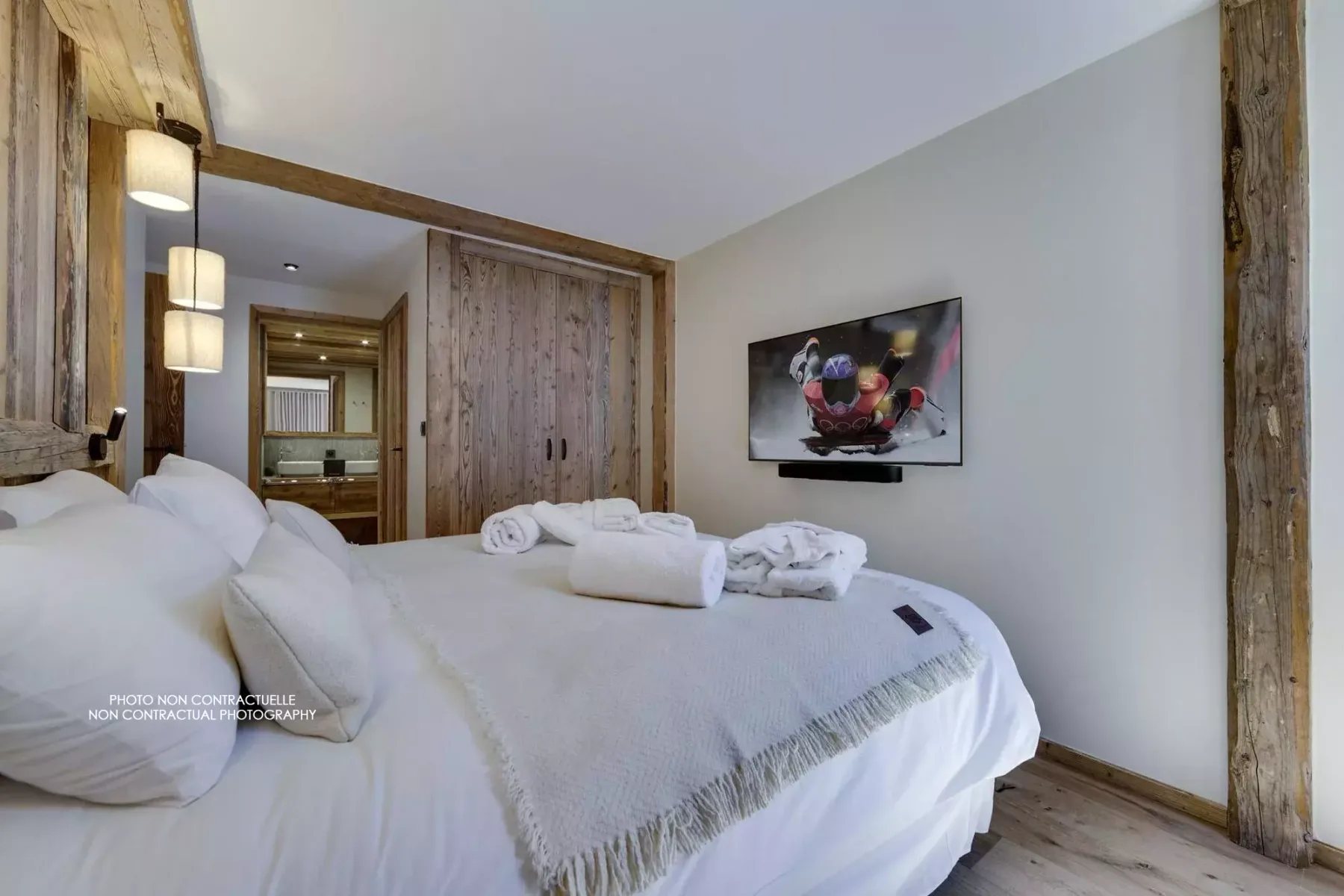 A bedroom with a neatly made bed and a framed artwork on the wall.