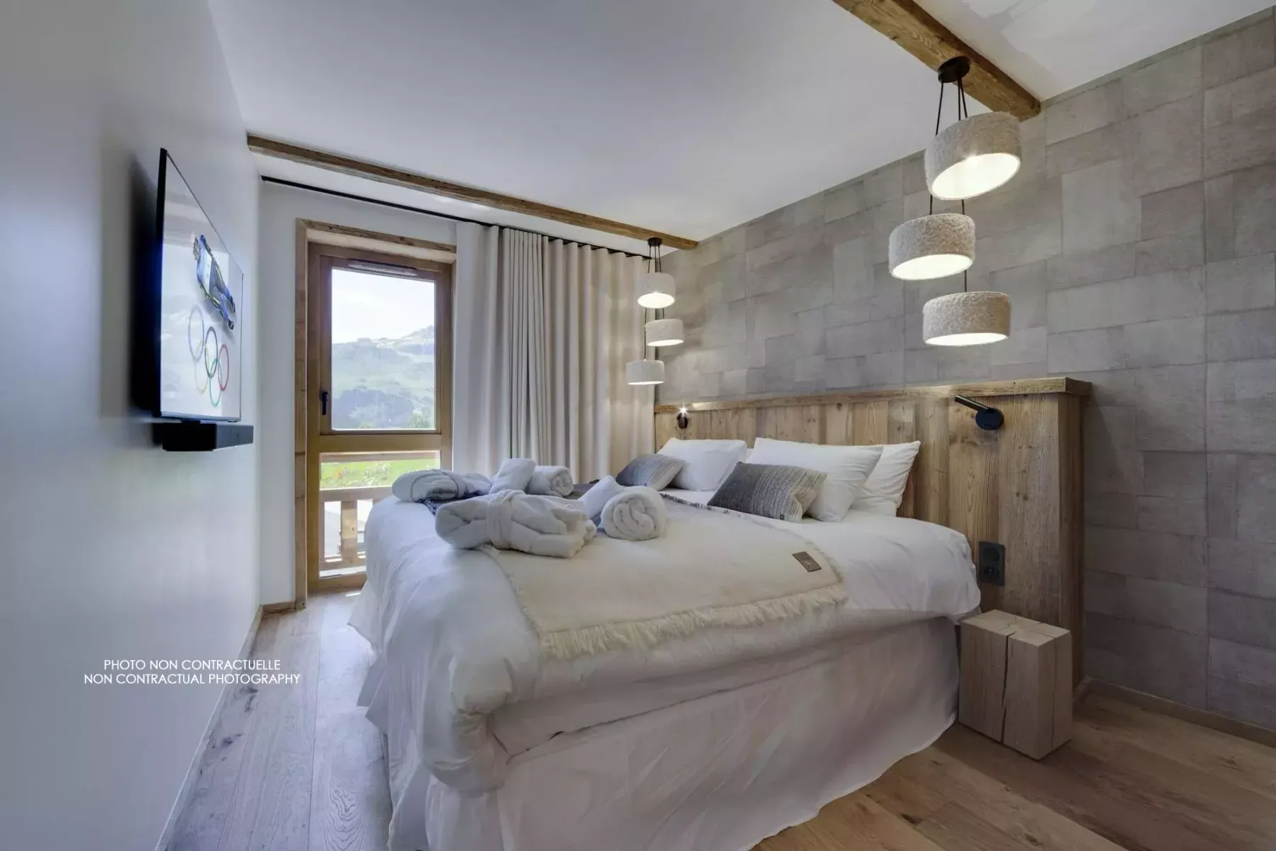 A bedroom with a large bed, wood headboard, and hanging pendant lights.