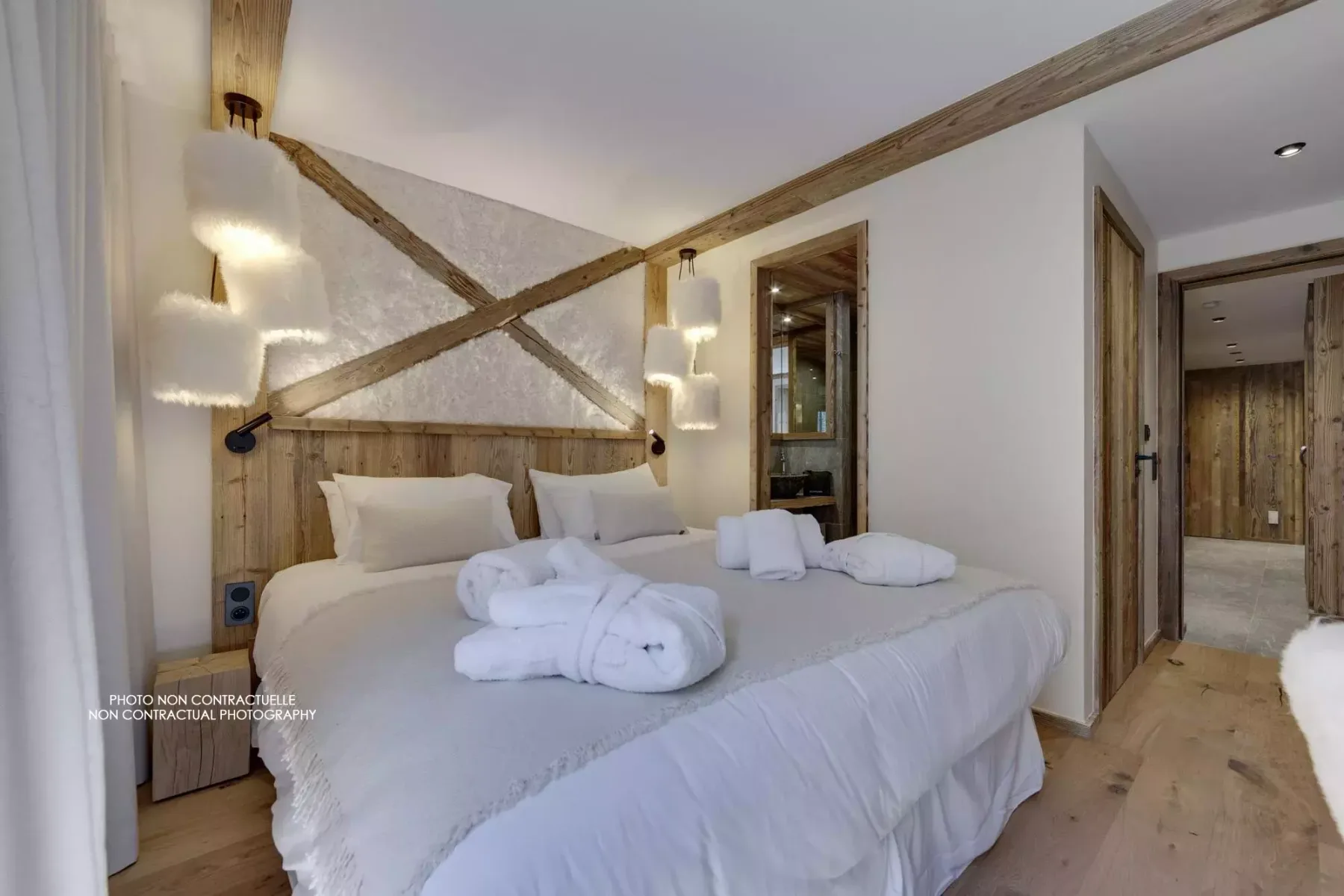 A bedroom with two beds, white linens, and rustic wooden beams.