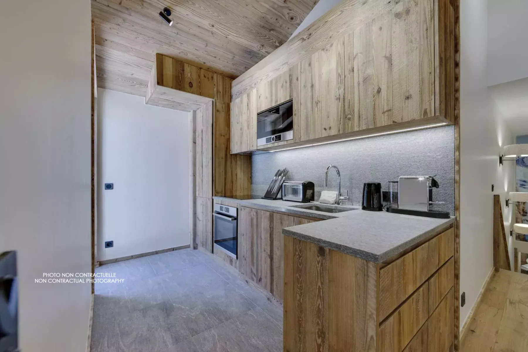 A compact kitchen with wood cabinetry, a countertop, and built-in appliances.