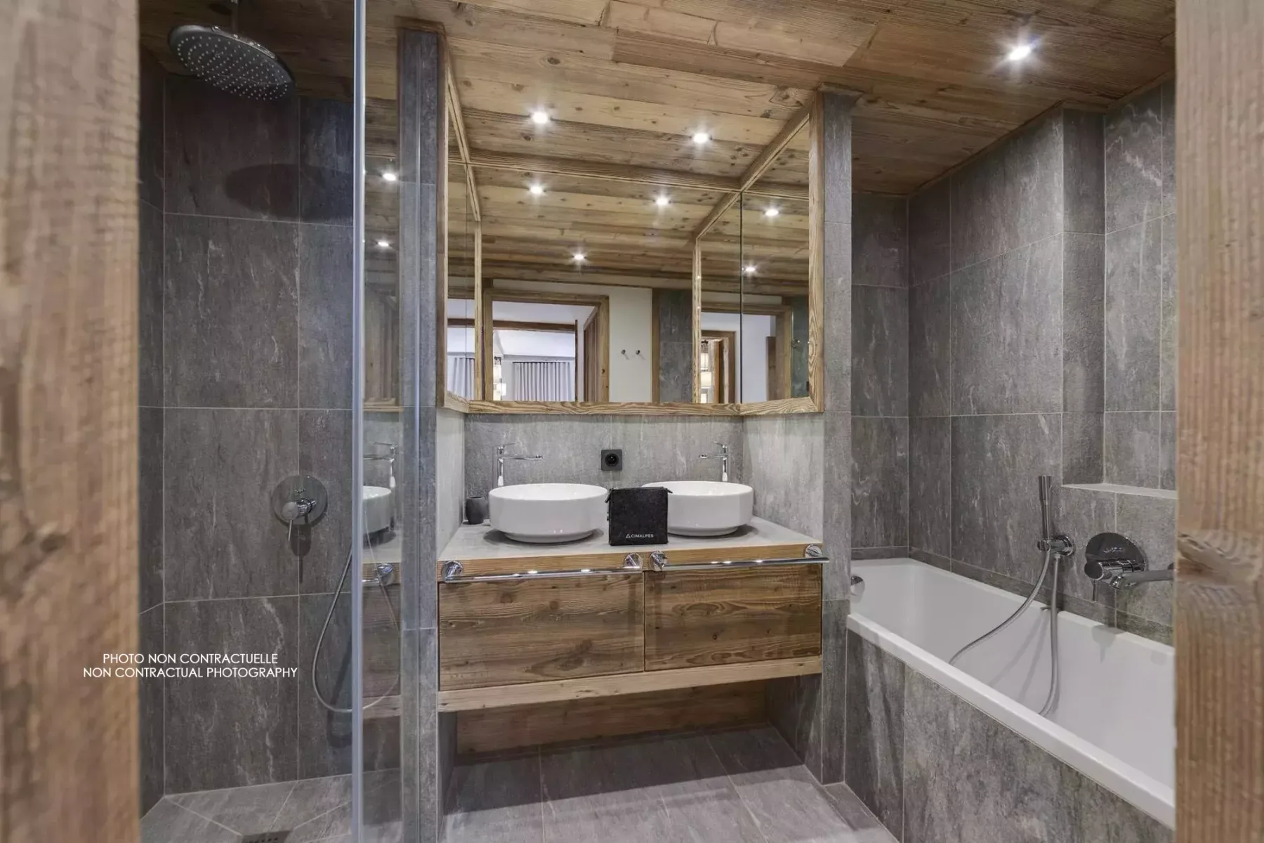 A tiled bathroom with a bathtub, shower, and wooden vanity.
