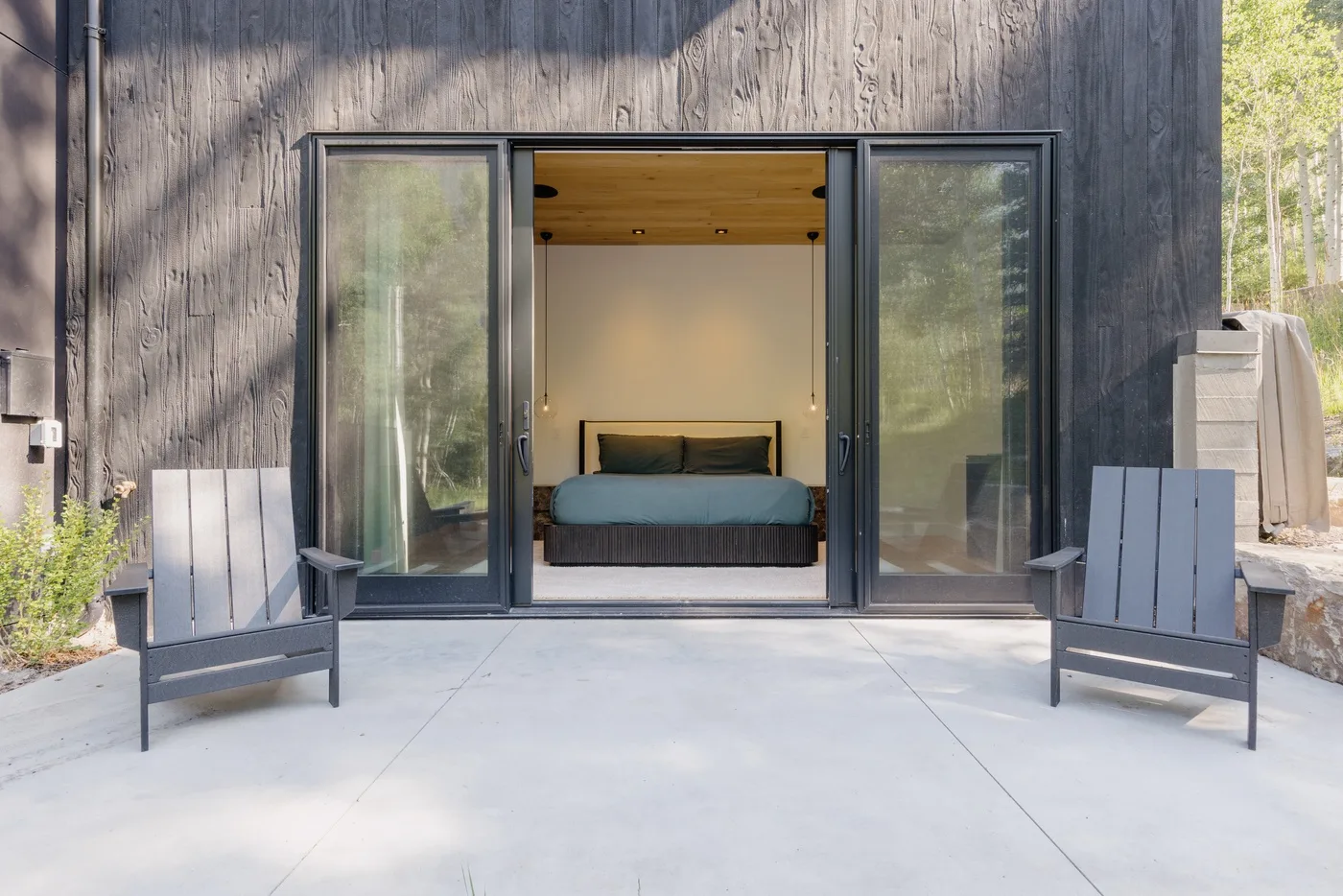 Un dormitorio se abre a un patio de concreto con dos asientos al aire libre.