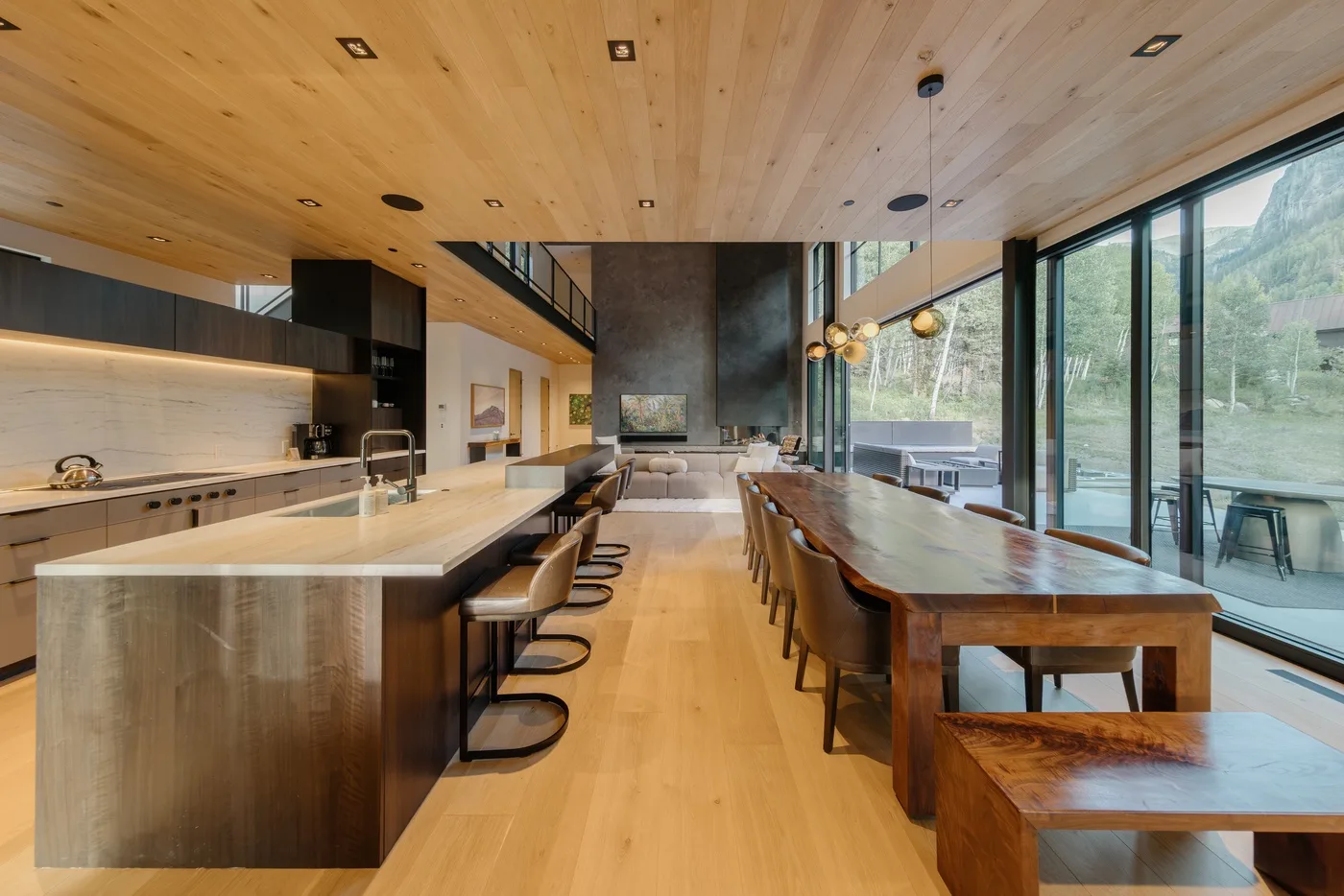 Una cocina y comedor diáfanos y modernos, con una isla larga y una mesa de madera.