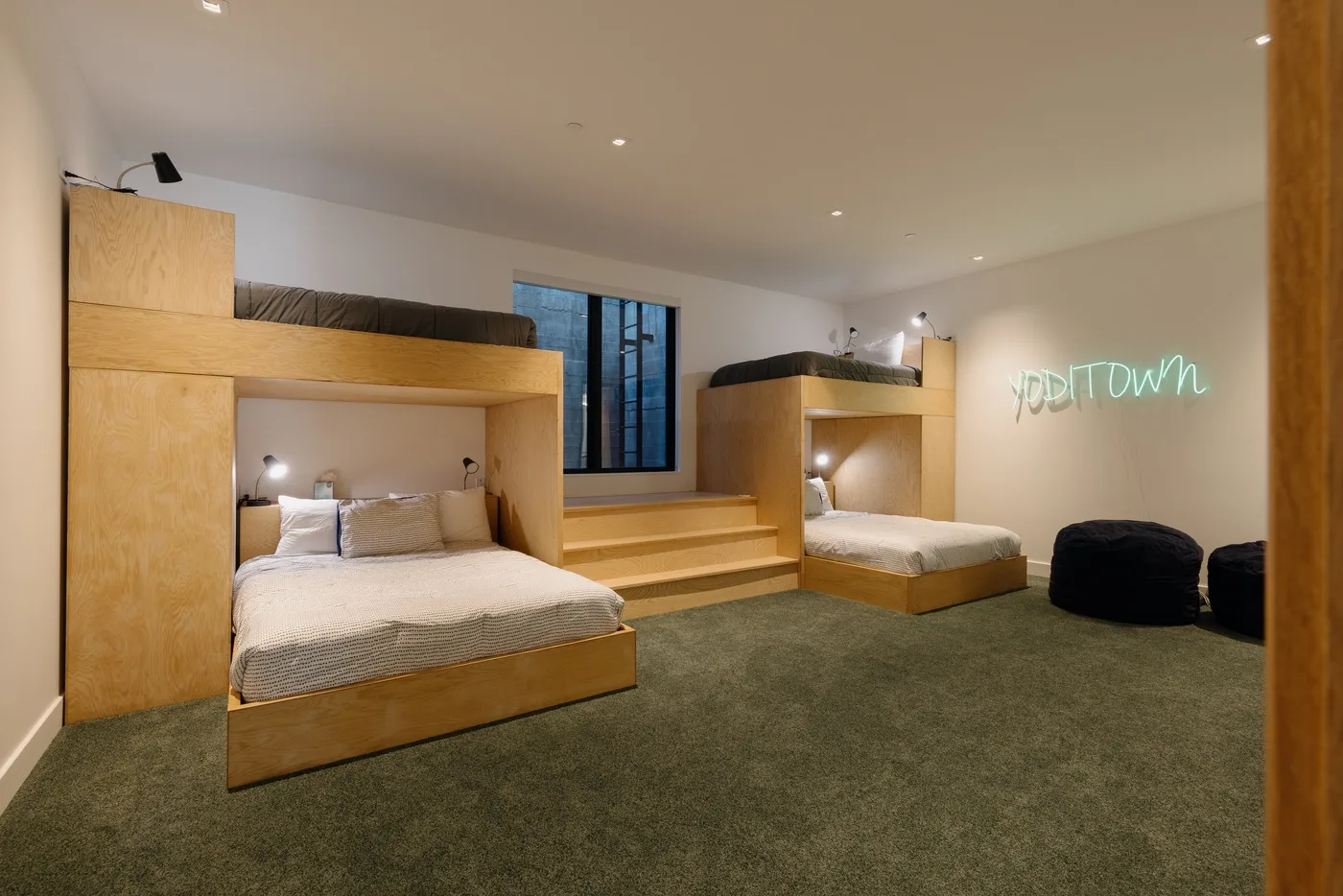 Un dormitorio con espacios para dormir empotrados, una ventana central y alfombra verde.