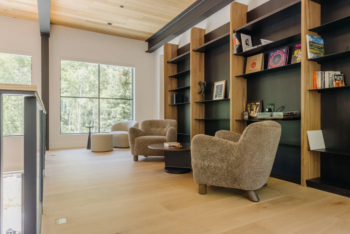 Una sala luminosa con asientos tapizados, estanterías empotradas y grandes ventanas.