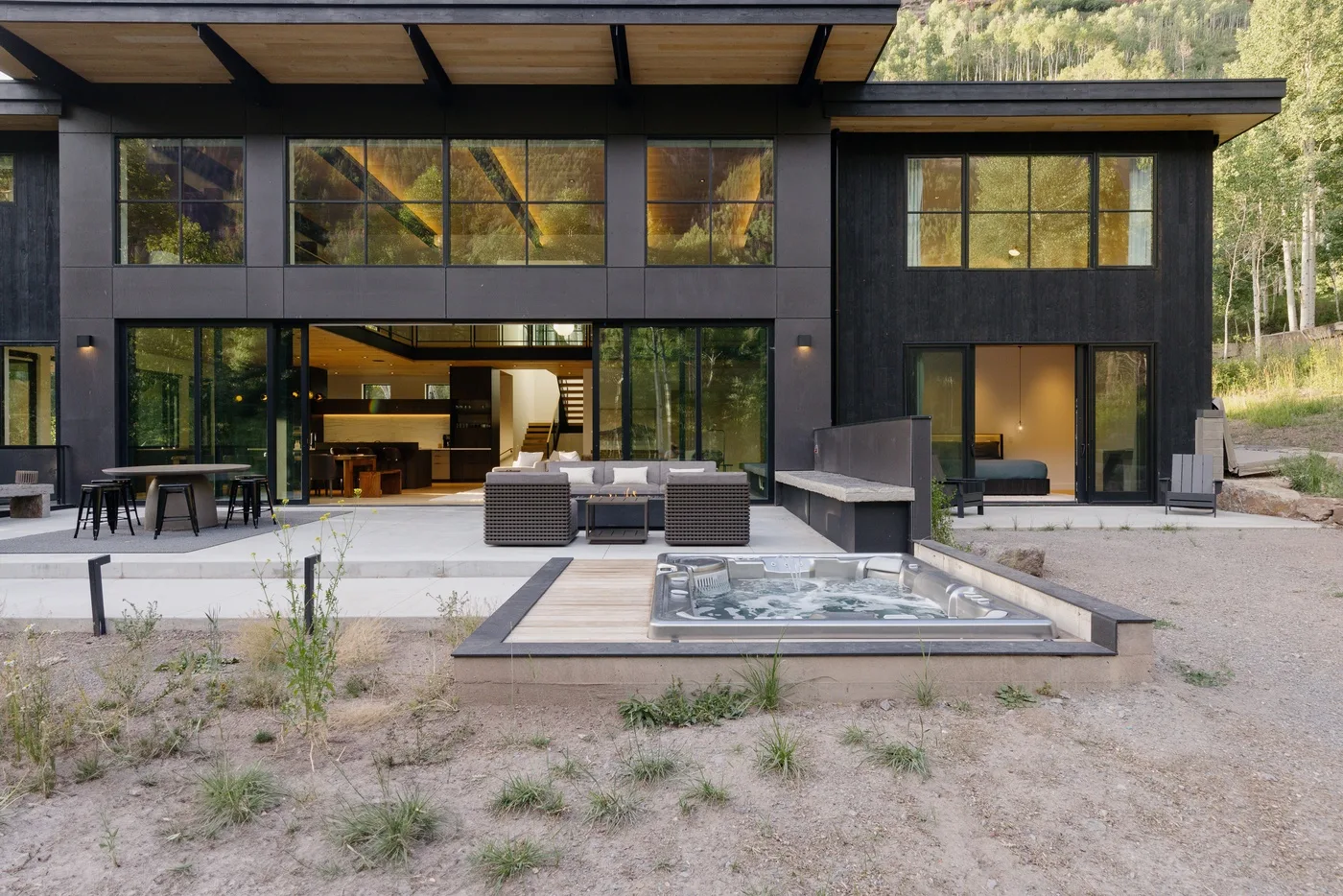 Una casa moderna se abre a un patio con asientos al aire libre y un elemento de agua integrado.