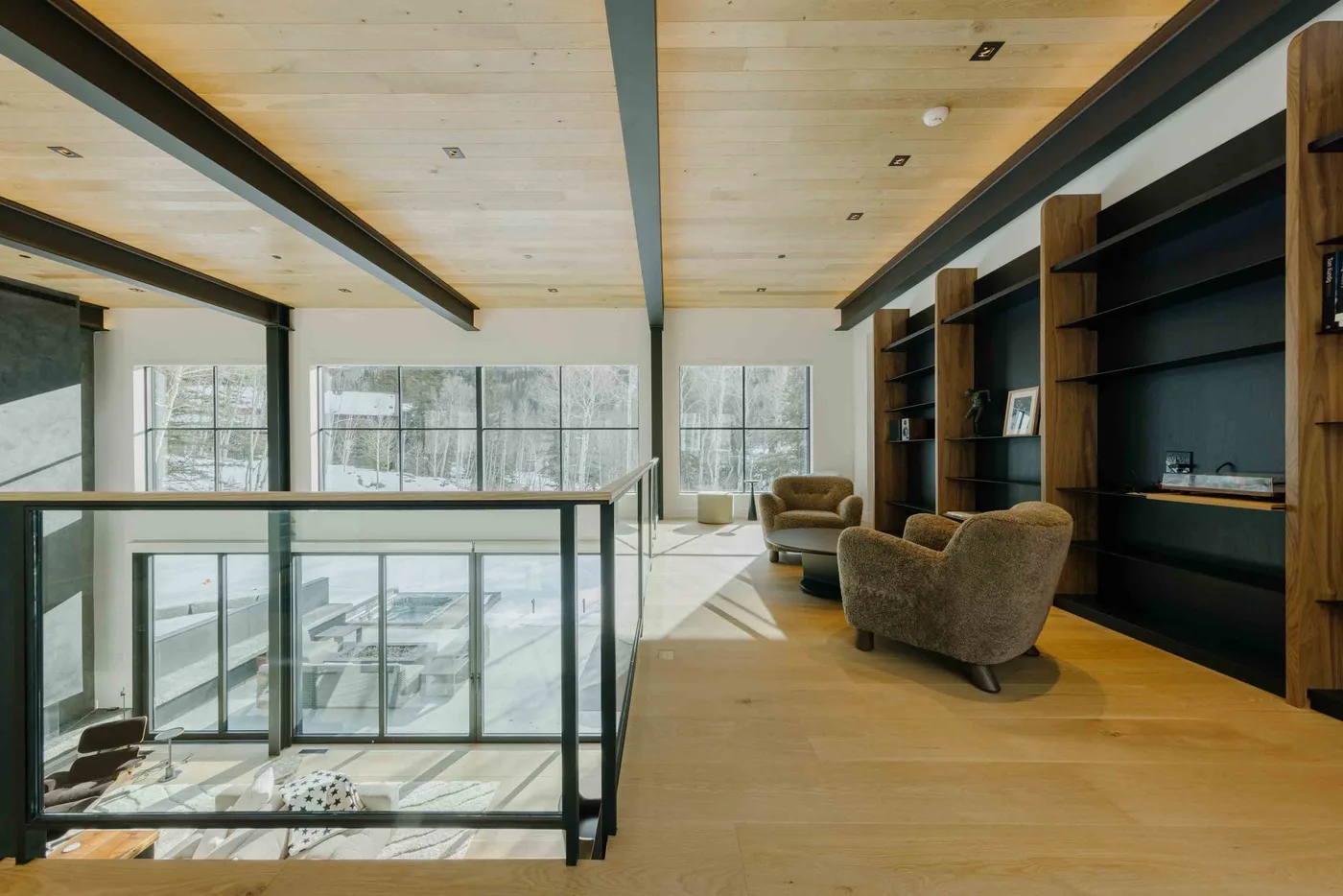Una sala luminosa con grandes ventanas, estanterías abiertas y asientos.