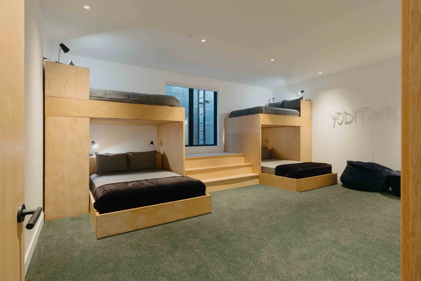 Un dormitorio con plataformas elevadas para dormir y una ventana central.