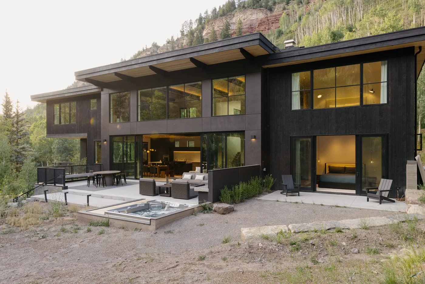Una casa moderna con grandes ventanales da a un patio con piscina.