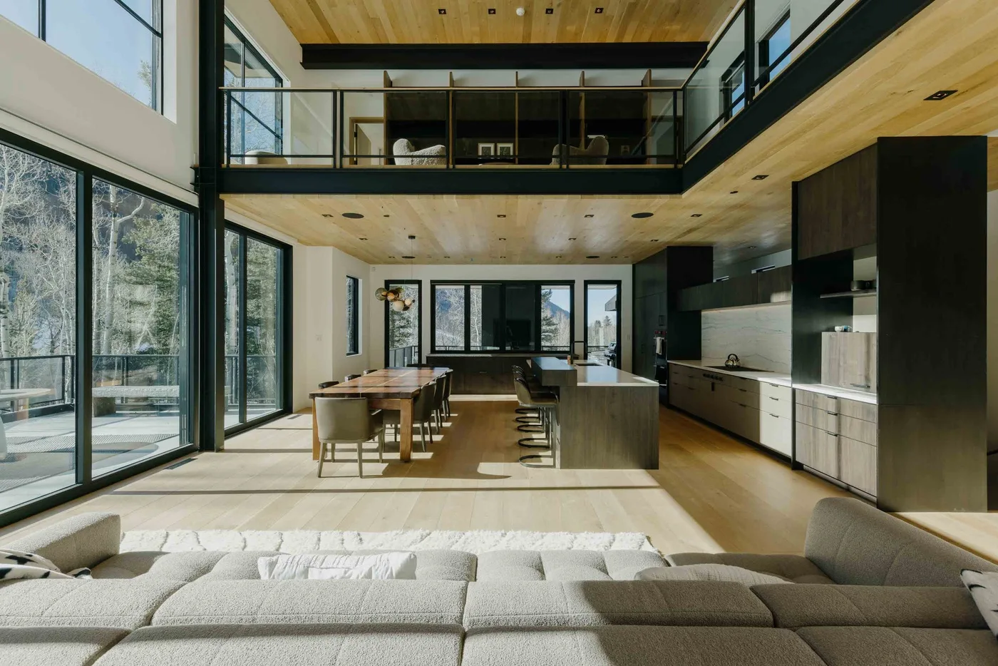 Amplia sala de estar de concepto abierto con cocina, mesa de comedor y ventanas altas.