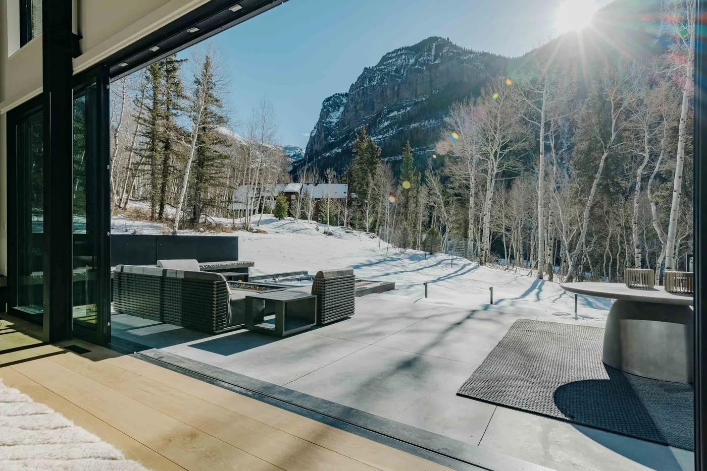Un patio pavimentado con asientos da a un paisaje montañoso y boscoso cubierto de nieve.