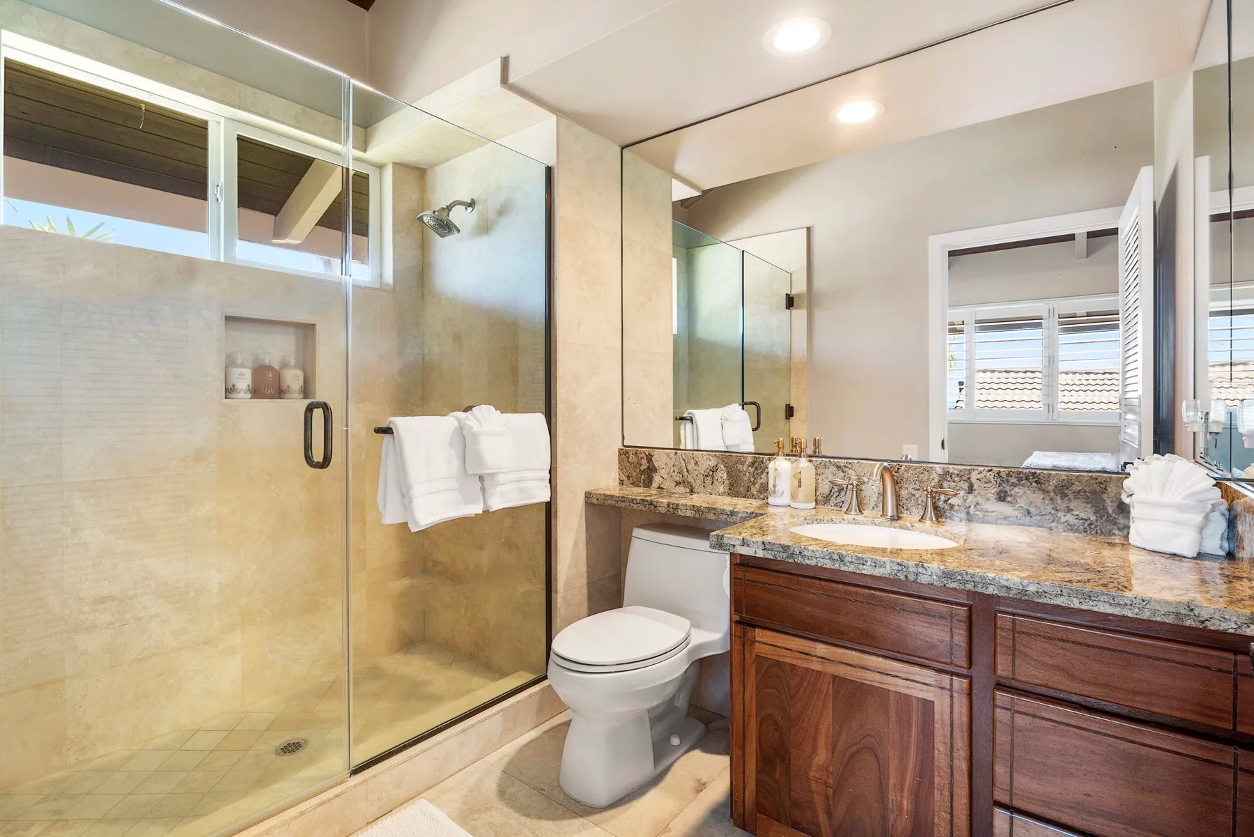 Un baño con ducha de vidrio, inodoro y lavabo con mueble.