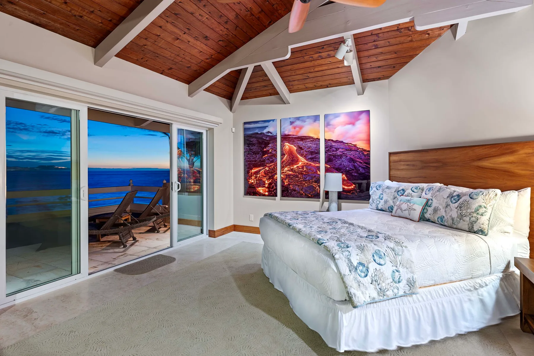 Un dormitorio con una cama grande, puertas corredizas de vidrio y vistas al mar.