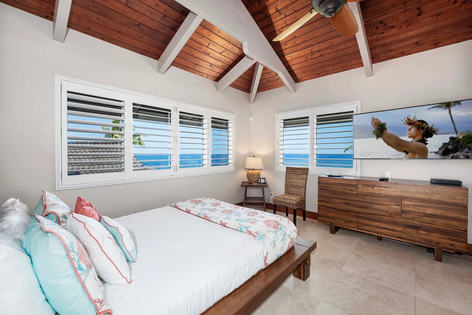 Un dormitorio con una cama grande, ventanas con persianas y techo revestido de madera.