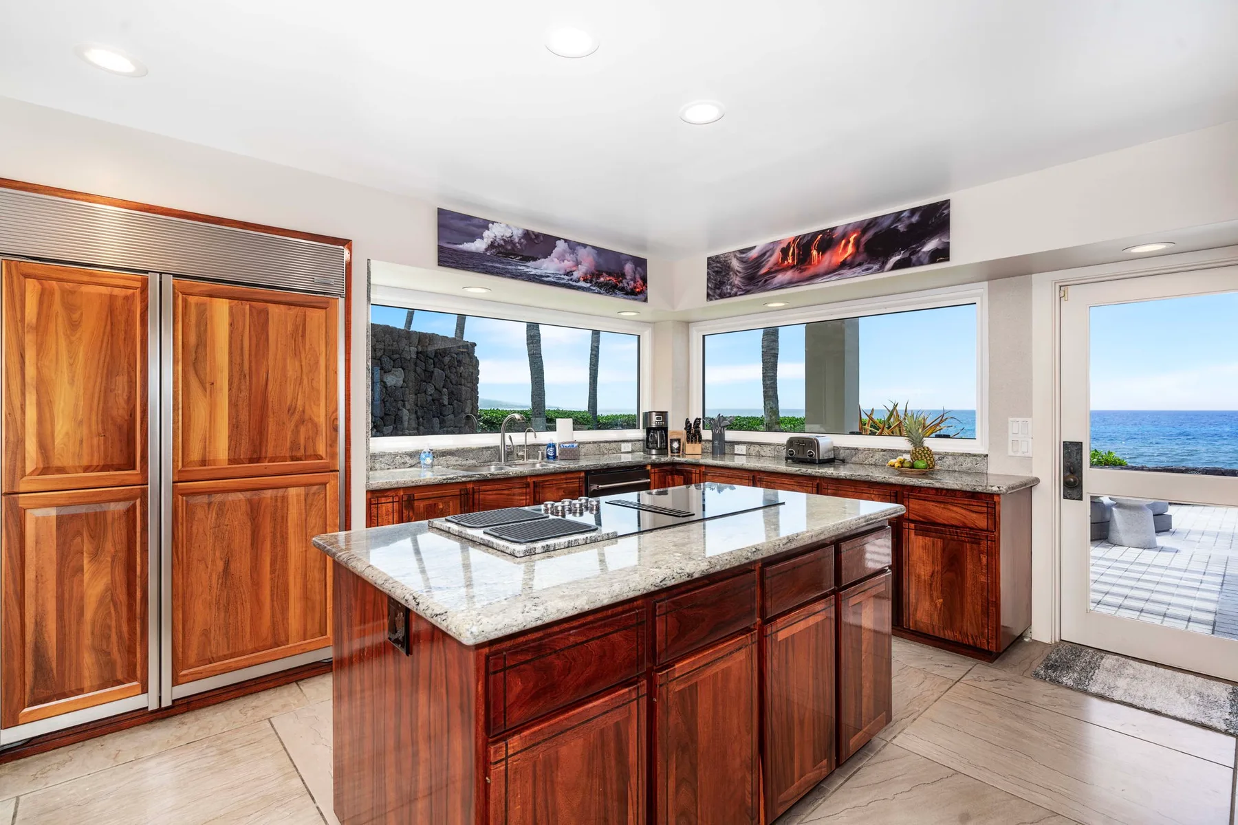 Una cocina con gabinetes de madera y una isla central da al océano.