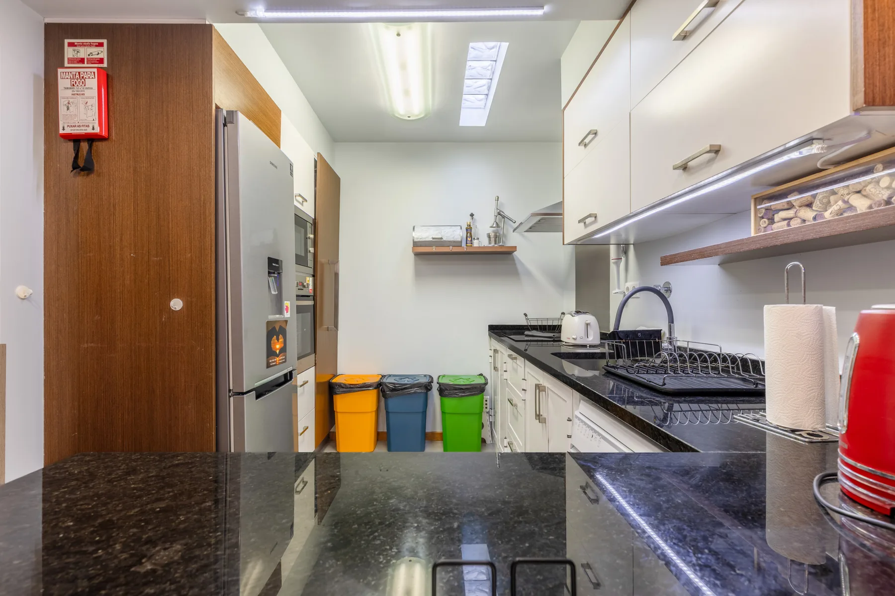 A narrow kitchen with white cabinets, a sink, and a dark countertop.