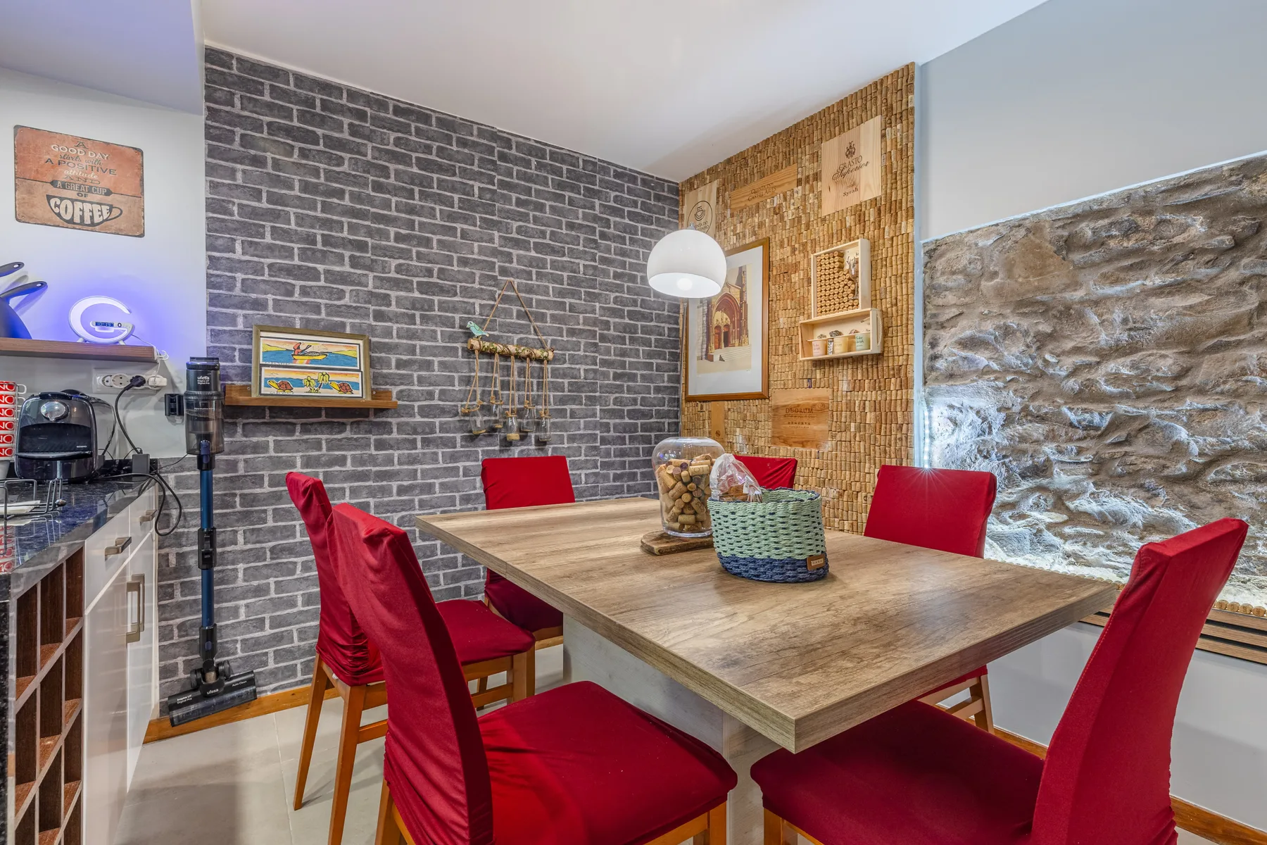 A dining area with a wooden table and red seating beside a stone wall.