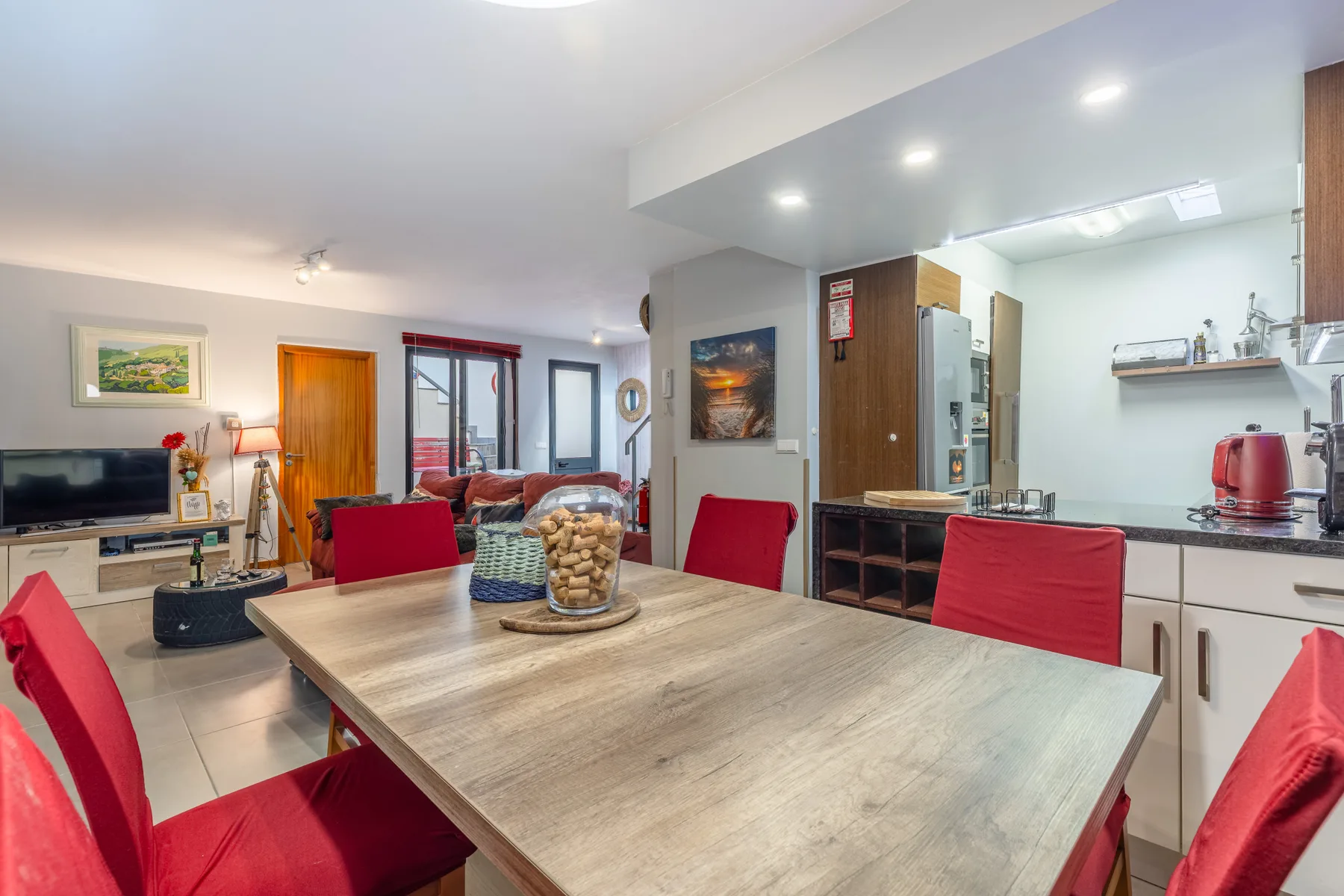An open-plan dining and living area has a large table with red seating.