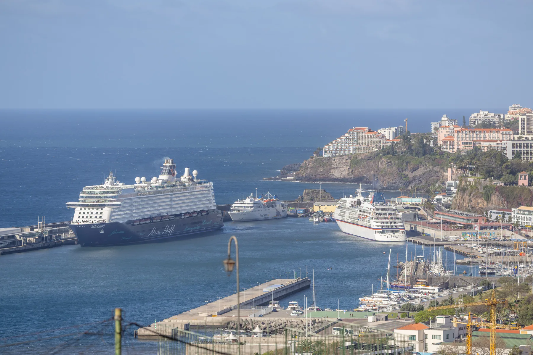 A harbor with cruise ships and smaller boats beside the coastline.