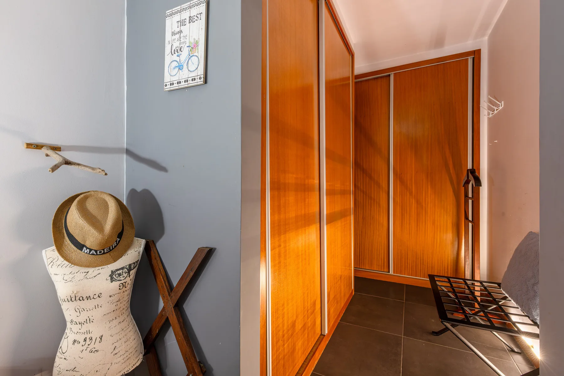 A narrow dressing area with wooden wardrobes and a hat displayed on a dress form.