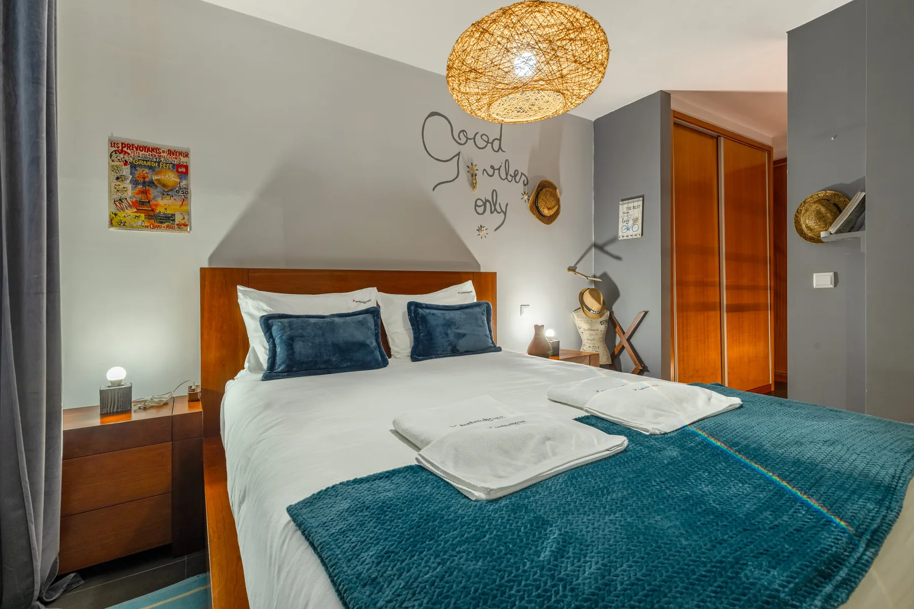 A bedroom with a neatly made bed and teal bedspread.