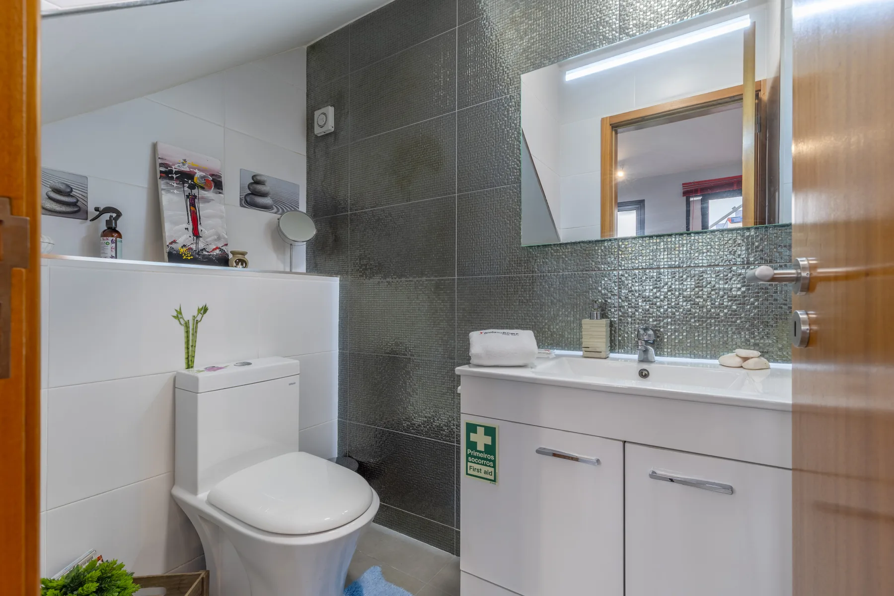 A bathroom with a toilet, sink, and large mirror.
