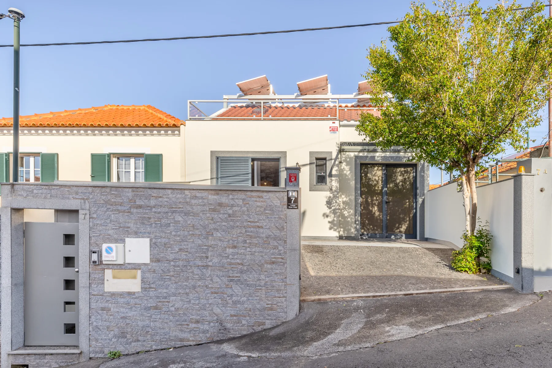 A house entrance with a stone wall and a paved driveway.
