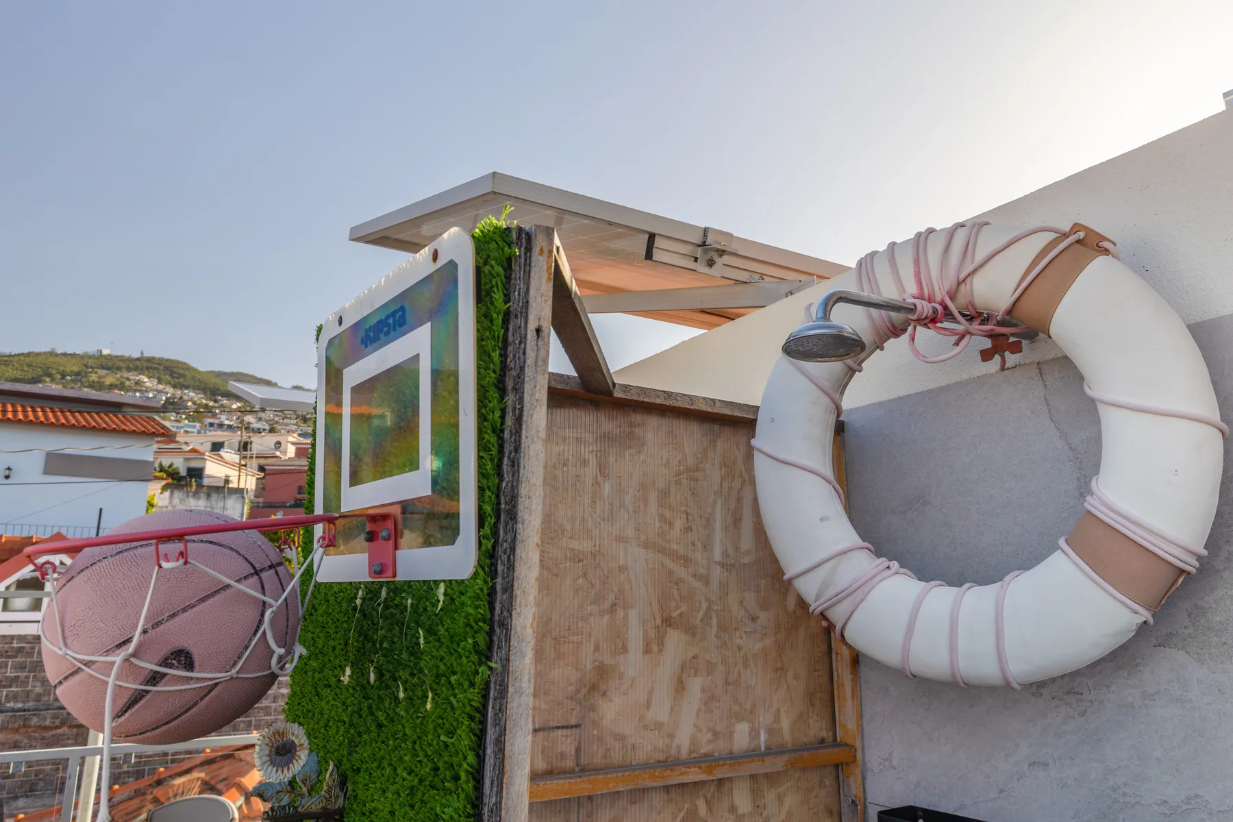 A rooftop terrace area has a large life ring mounted beside a shower.