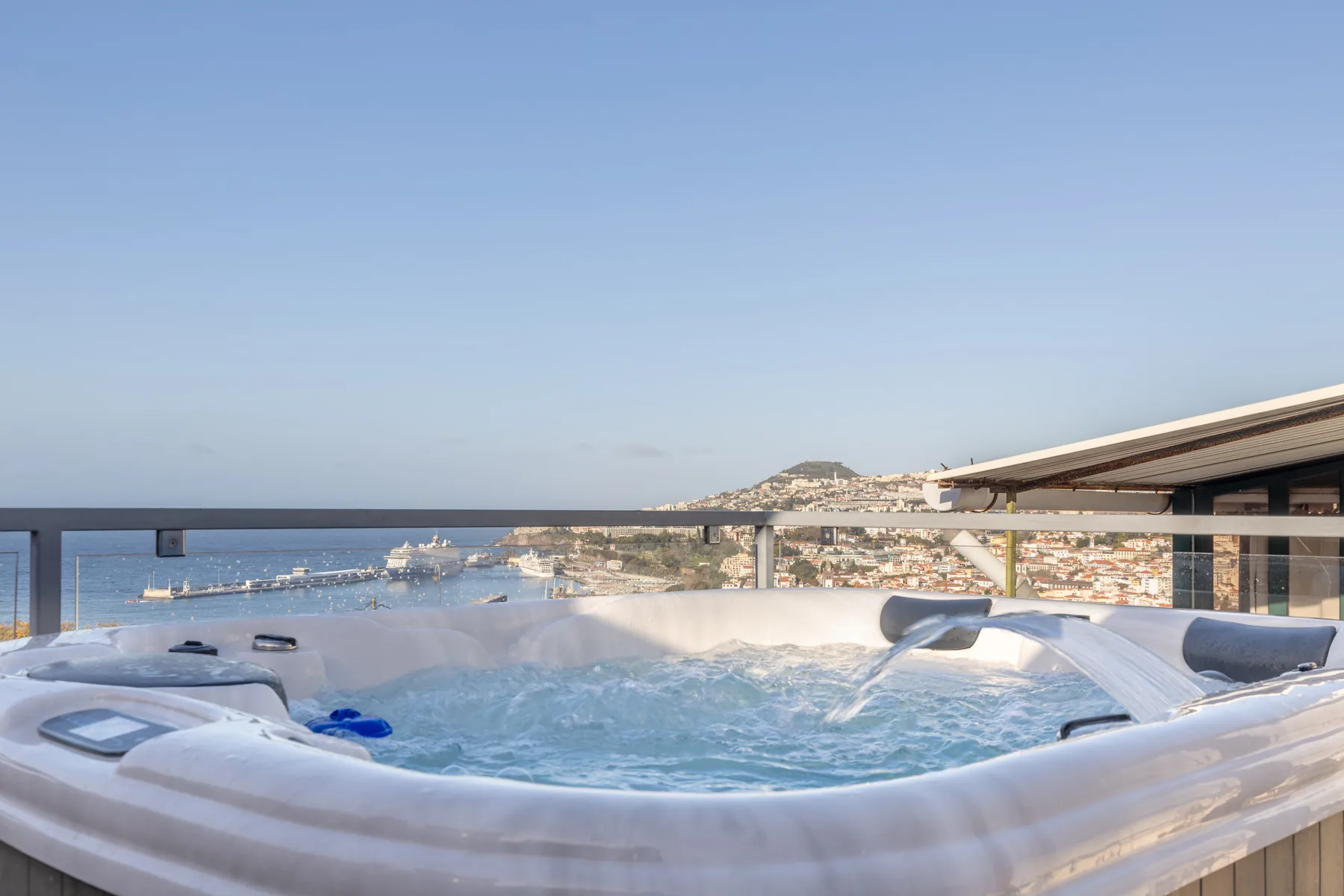 A rooftop hot tub overlooks the harbor and coastal city.
