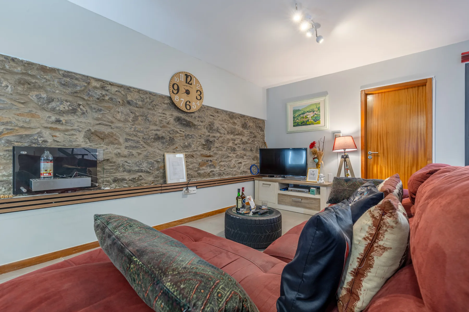 Living room with seating, a television, and a stone accent wall.